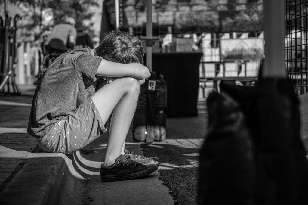 sad child in foster care sitting on curb visually upset